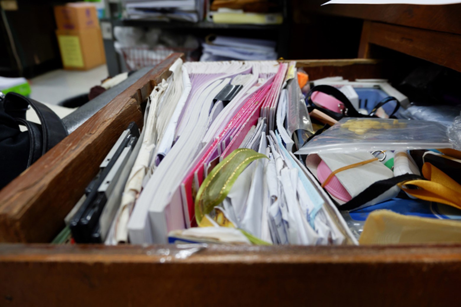 A junk drawer crammed with papers, books, office supplies, and other clutter.